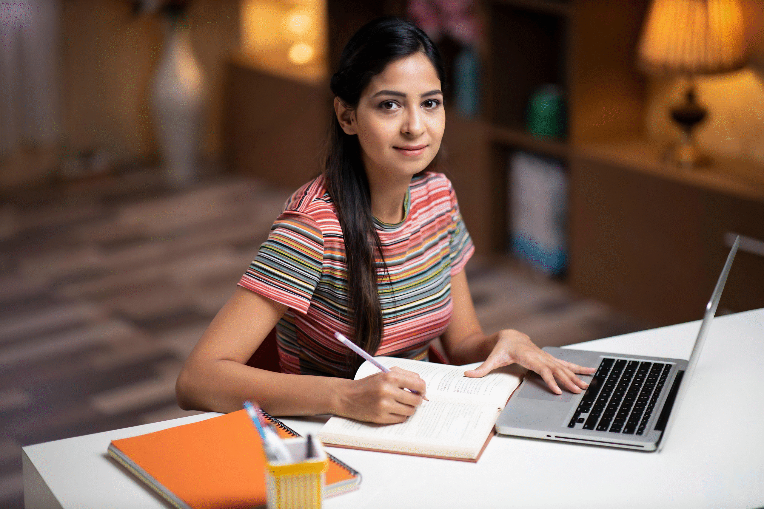 "Indian student studying independently with a laptop and books, demonstrating self-learning, confidence, and personal growth in a flexible learning environment."