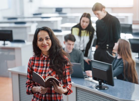 Brown colored book in hands. Group of young people in casual clothes working in the modern office.